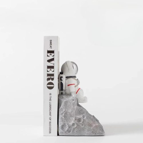 Le serre livre astraunote gris est un serre-livre décoratif en forme d'astronaute sur un rocher gris ressemblant à une lune. Il est idéal pour tout amateur de livres ou pour ajouter du charme à votre étagère.