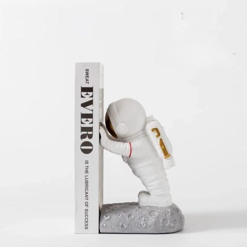 Le serre livre découverte du monde blanc représente un petit astronaute en combinaison spatiale appuyé sur un livre blanc étiqueté EVEREO, posé sur un socle gris semblable à une lune - un Accessoire de lecture idéal pour toute Bibliothéque.