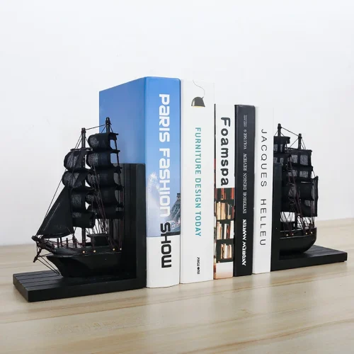 Le serre livre voyage, un ensemble de serre-livres noirs en forme de bateau, soutient les livres sur une étagère en bois clair sur un fond blanc uni.