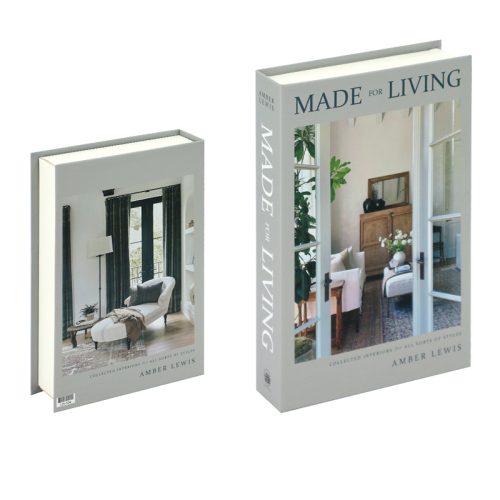 Deux exemplaires du livre Made for Living d'Amber Lewis sont exposés, l'un de face et l'autre de biais. La couverture présente un salon lumineux et stylé, avec un fauteuil blanc, une table en bois et des fenêtres de style roman qui laissent entrer la lumière naturelle.