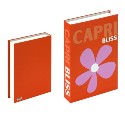 Deux livres sont posés debout sur l'étagère. Le livre de gauche a une couverture rouge unie et des pages blanches. Le livre de droite, plus grand, porte l'inscription "CAPRI BLISS" en caractères gras et une grande fleur violette avec un centre rose pâle sur le devant.
